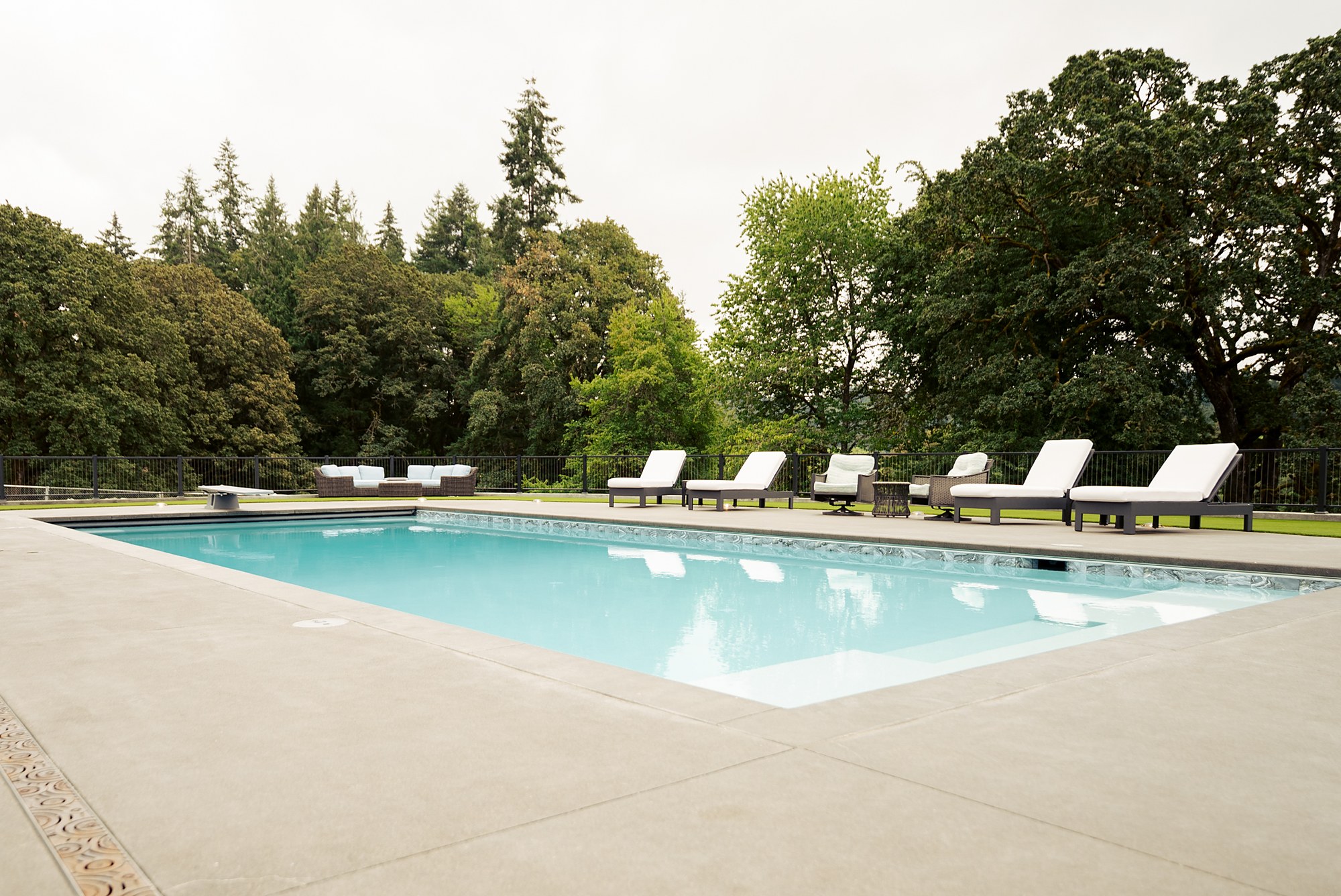The pool and loungers beneath mature oaks