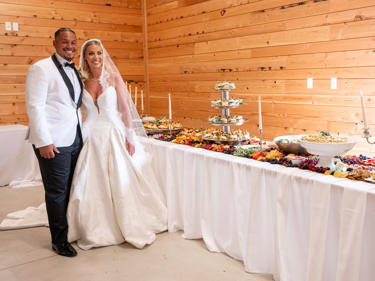 A newly married couple beside the grazing table in the barn