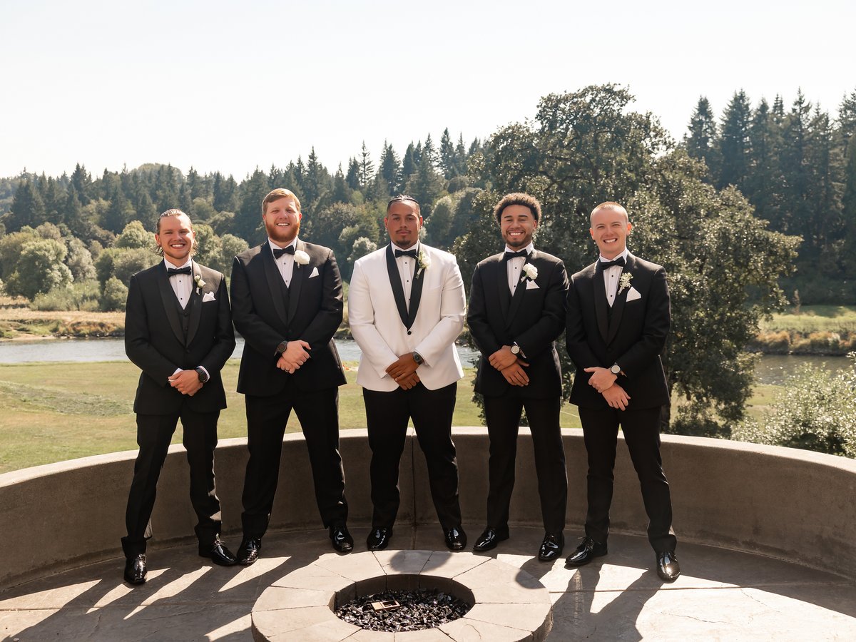 Groomsmen gathered at the fire pit above the river