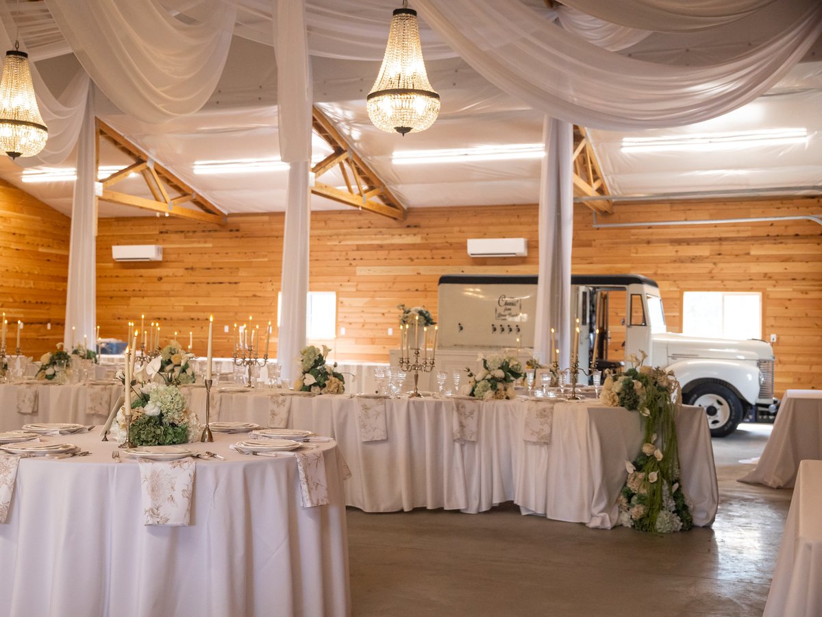 The barn dressed for a reception in white drapery and chandeliers